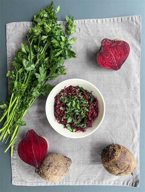 Nuožulnus vaizdas ant šviežių burokėlių krūvos tamsioje medinėje lentelėje.