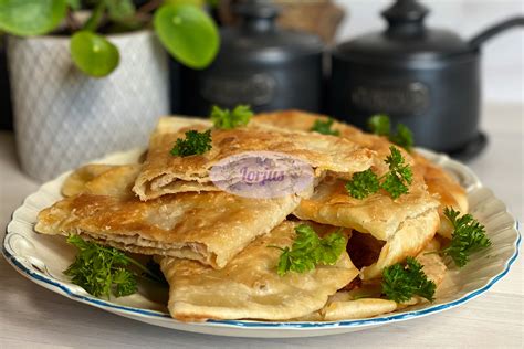 Čeburekai patiekiami ant lėkštės su žalumynais