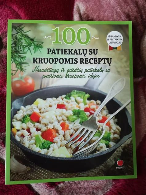 Moters rankos, verčiančios receptų knygą su ryškiomis patiekalų nuotraukomis