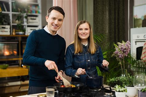 Šeimos nariai kartu gamina virtuvėje, fotografuoja patiekalą