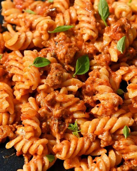 Makaronai su šonine ir pomidorais, papuošti sūriu ir bazilikais