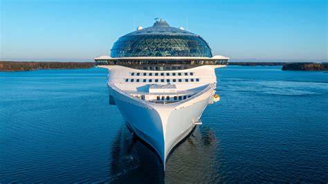 Modernus kruizinis laivas Viduržemio jūroje su pakrantės miesteliu fone