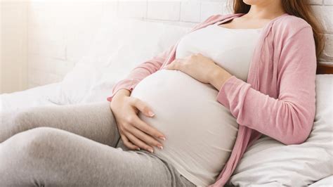 Nėščia moteris su puodeliu kmynų arbatos