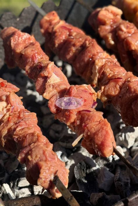 Paruošti kiaulienos šašlykai ant iešmų, kepantys ant grotelių