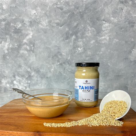 Sezamų sėklų dubenėlis šalia naminės tahini pastos stiklainio