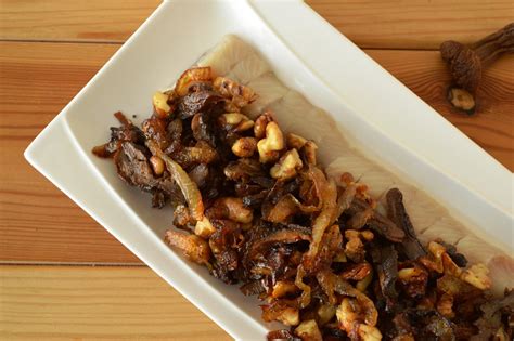 Nuotrauka su silkės gabalėliais, užklotais karamelizuotais svogūnais ir riešutais