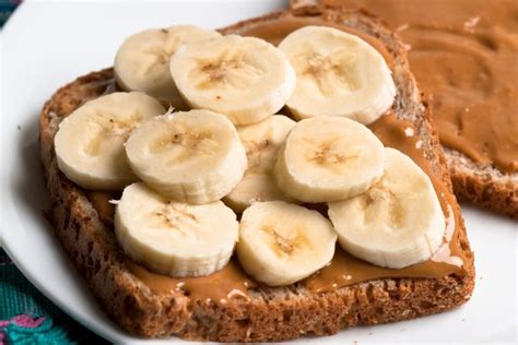 Skrudinta duona su riešutų sviestu ir įvairiais priedais: bananais, braškėmis, mėlynėmis, sėklomis