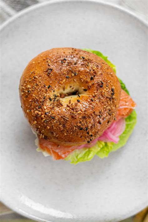 Beigeliai su lašišos gravlax, sūrio kremu ir marinuotais svogūnais