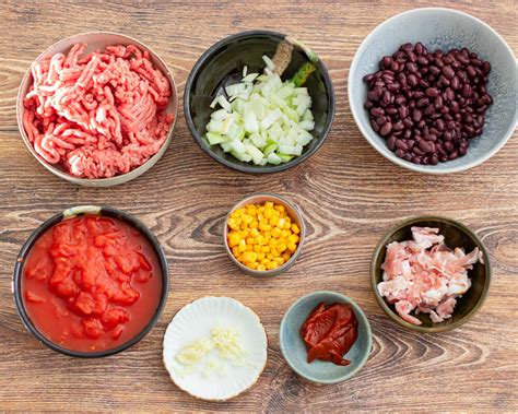 Įvairūs čili troškinio ingredientai: faršas, pupelės, pomidorai, paprika